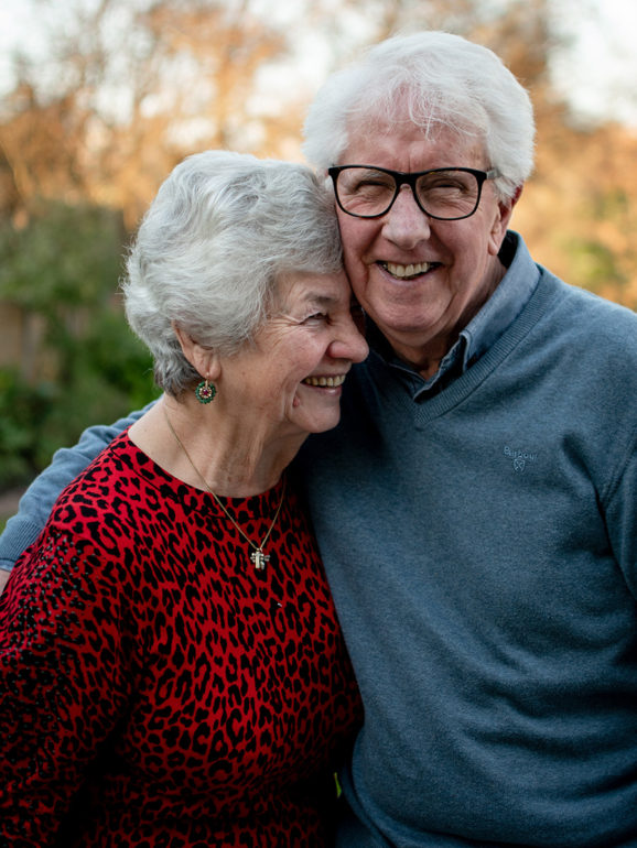 Older couple hugging and smiling.