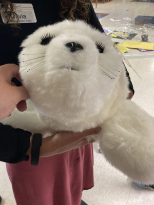 A person holds a therapeutic robot that looks like a baby harbor seal.