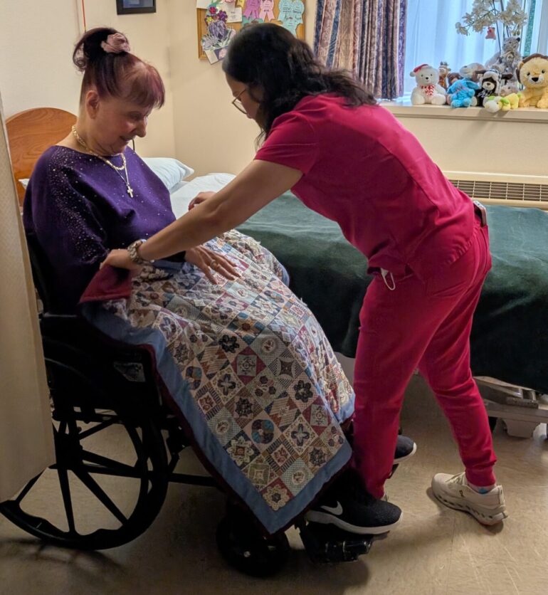 A CHCC nursing assistant places a lap blanket on a long-term care resident.