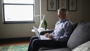 Older man sitting on couch viewing online courses for seniors.